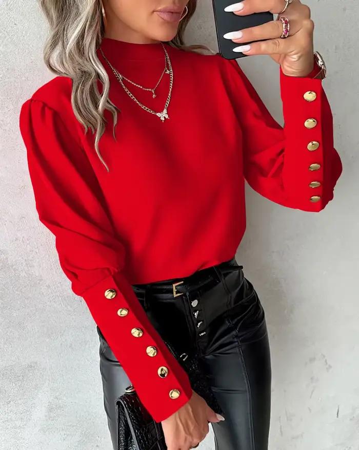 Chemise élégante à col haut et manches longues bouffantes avec boutons dorés décoratifs sur les poignets et tissu lisse