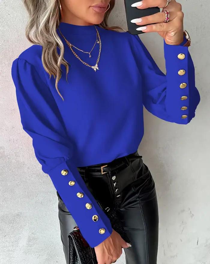 Chemise élégante à col haut et manches longues bouffantes avec boutons dorés décoratifs sur les poig