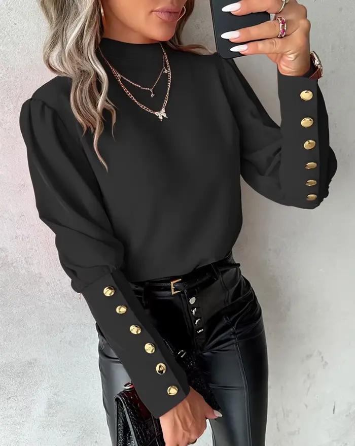 Chemise élégante à col haut et manches longues bouffantes avec boutons dorés décoratifs sur les poignets et tissu lisse
