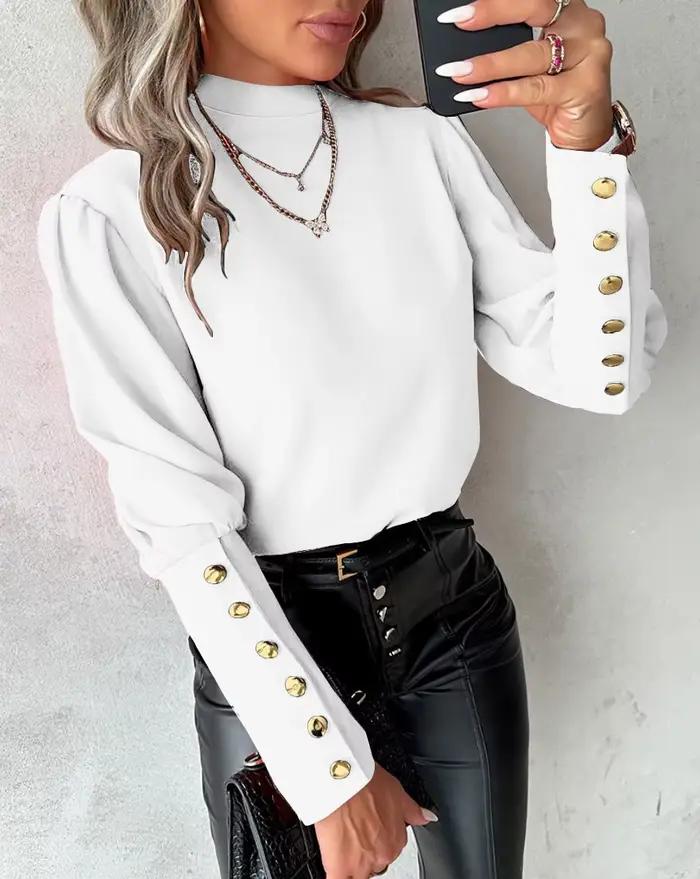 Chemise élégante à col haut et manches longues bouffantes avec boutons dorés décoratifs sur les poignets et tissu lisse